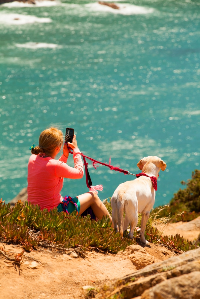 Girl taking a photograph with her smartphone at the ocean coast.